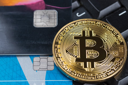 Gold physical Bitcoin on computer keyboard with credit cards. Cryptocurrency shopping abstract concept.の写真素材