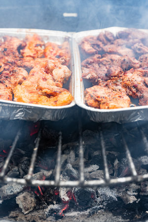 Pork, beef and chicken meat on a barbeque charcoal grill with smoke. Delicious summer season outdoor meal preparation.の写真素材