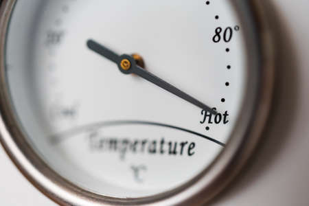 Temperature meter with needle indicating hot or high. Sale, new product or summer time abstract concept. Shallow depth of field.の写真素材