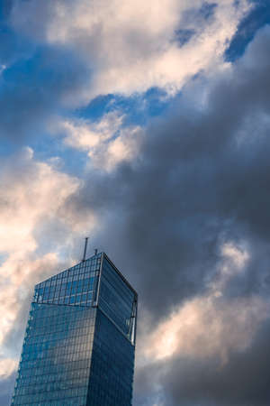 Modern glass office business building against dramatic blue and yellow sky. Vertical orientation.の写真素材