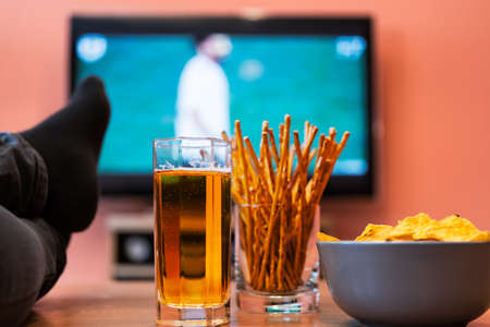 Watching football or soccer on television with beer, chips and breadsticks.の写真素材