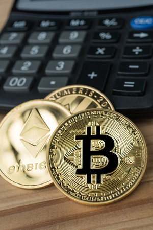 Golden physical Bitcoin, Ethereum and Litecoins on calculator on wooden background. Cryptocurrency...