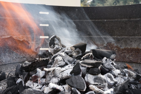 Black charcoal burning with smoke and fire in a barbecue grill. Delicious meal preparation.の写真素材