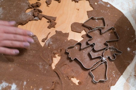 Young woman making gingerbread cookies for Christmas. Dough and baking biscuit cutters on a wooden...