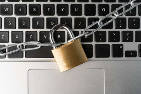 Padlock with chain on a laptop computer keyboard. Cyber security abstract concept.の写真素材
