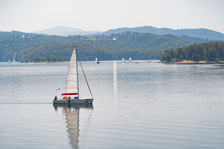 Solina, Poland - June 24, 2019: Sailboat swimming on an artificial lake near Solina Dam.のeditorial素材