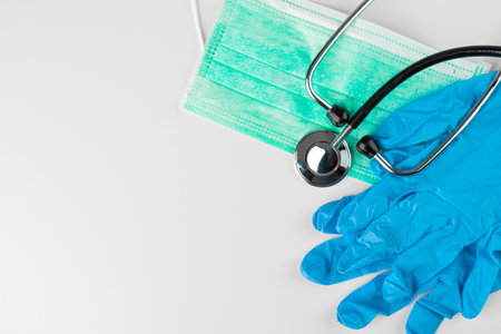 Green protective face mask, stethoscope and gloves on a white background. Copy space on the left.の写真素材