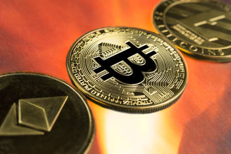Physical Bitcoin, Litecoin and Ethereum gold coins with fire or flame background. Cryptocurrency bull market growth with rising prices.の写真素材