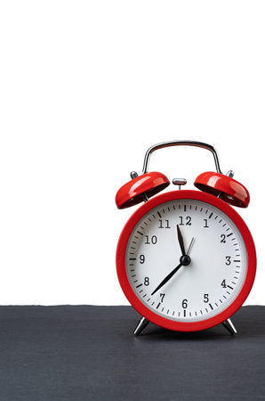 Vintage red alarm clock on dark slate plate isolated on white background. Copy space on the top...