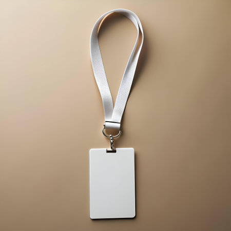 Blank white ID card on a white lanyard with a silver clip. isolated on a beige background. Perfect for mockup designs. branding. and corporate identity.の素材