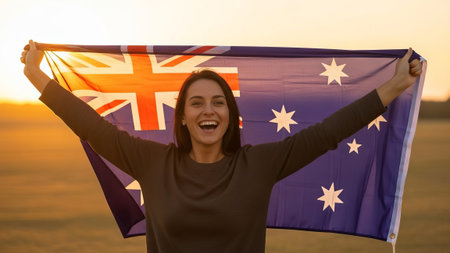 Woman with Australian flag at sunset, outdoors, happy.の素材