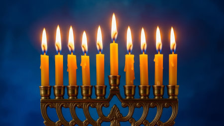 Menorah with nine lit yellow candles, blue background, festive holiday lightingの素材