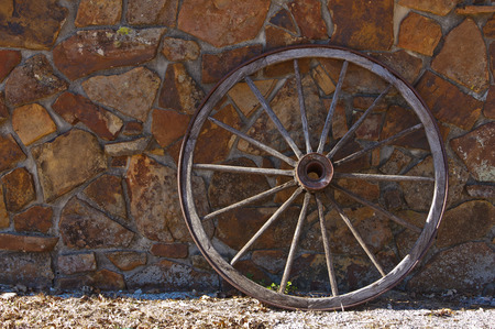 An old wagon wheel against a stone wallの写真素材