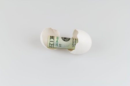 Money in an eggshell against a white background 