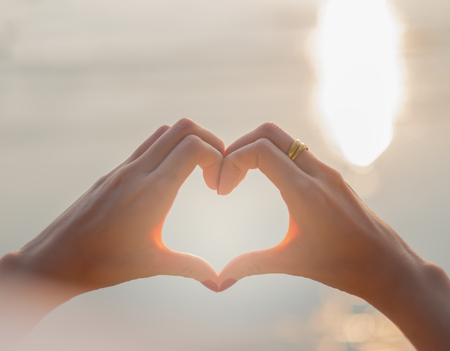 Woman hand heart shape in sunset on the beach. Love conceptの写真素材
