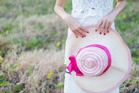 Young woman holding a hat in the parkの写真素材