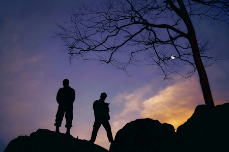 Silhouette of two soldiers on the top mountain at twilightの写真素材