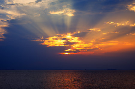 Sunset rays through a cloudy dark sky over the lake