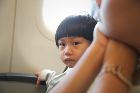 Little boy sitting at window seat in airplane : looking at cameraの写真素材