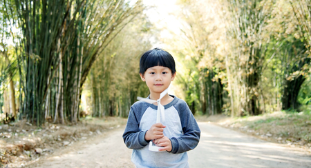 Little asian boy walking with wind turbine toy on bamboo tunnel road : Thailandの写真素材