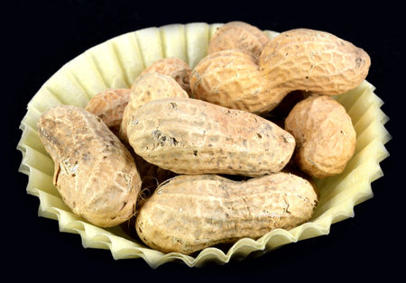Peanuts in the shell in a yellow paper cup.