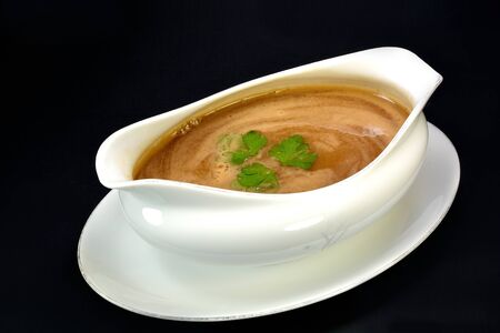Gravy in a bowl with parsley on a black background.の写真素材