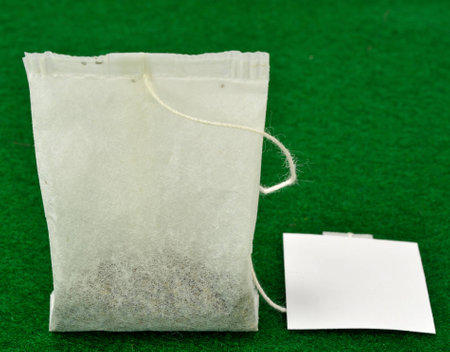 Single tea bag on a green background.の写真素材