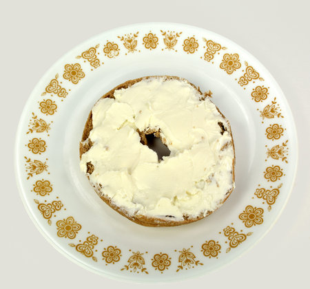 Bagel with cream cheese on a plate on a white background.の写真素材