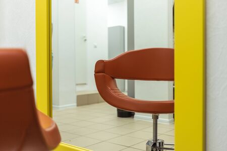 a chair in the barbershop opposite the mirror. chair of a pleasant shade. a chair for customers in a hair salon. Great mirror for customers. ordinary hairdresserの写真素材