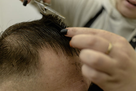 the man sits and he is cut. a mans haircut. womens hands of a hairdresser. scissors, comb, hair....