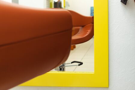 a chair in the barbershop opposite the mirror. chair of a pleasant shade. a chair for customers in a hair salon. Great mirror for customers. ordinary hairdresserの写真素材