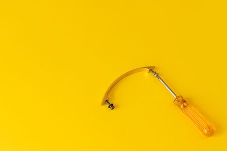 screwdriver with orange handle and a cabinet handle with bolts. handle for a closet with screws and a screwdriver nearby. yellow backgroundの写真素材