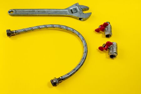 wrench and safety valves with red edges on a yellow background. home repairs for pipes. safety valves for pipe repair and safetyの写真素材