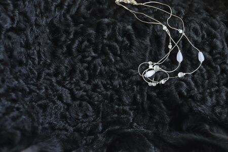 women's hand made necklace made carefully. costume jewelry lies on a black sheep skin, contrasting with it. natural light, shimmering and reflections. macroの写真素材
