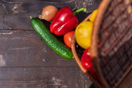 fresh harvest. freshly harvested vegetables and fruits lie on a wooden table. cucumbers, bell peppers, onions, lemon, tomatoes. beside the wicker basket.の写真素材