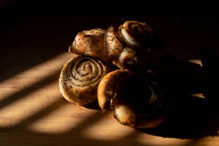 delicious crispy candied bagels with poppy seeds lie on a wooden Board, warmly illuminated by a beautiful warm light. a knife close to itの写真素材