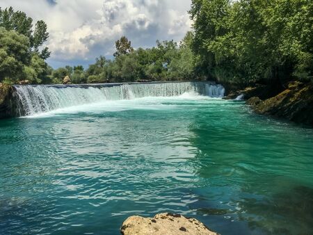 waterfall with dense vegetation nearby. Turkey, Antalya, Mediterranean Sea. There are no people near the waterfall. green forest and cloudsの写真素材
