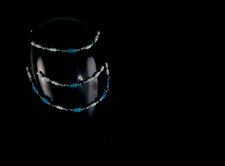 A necklace made by hand in an unusual way is presented of a portrait mannequin woman. On a dark background and highlighted at the back, the necklace glitters. Reflections. Not precious stones or metalの写真素材