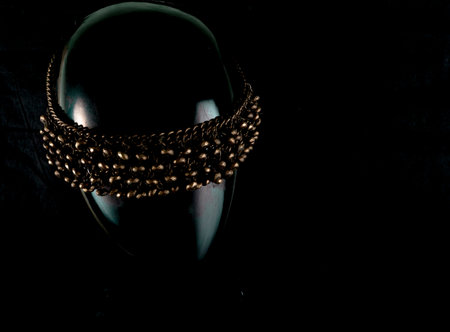 A necklace made by hand in an unusual way is presented of a portrait mannequin woman. On a dark background and highlighted at the back, the necklace glitters. Reflections. Not precious stones or metalの写真素材