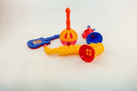 childrens bright colorful toys on a white background. group of musical instruments: saxophone, maraca, trumpet, guitarの写真素材