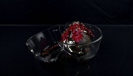jewelry in the form of a necklace lies on a dark background on an artificial translucent, reflecting crystal jewelry. next to the decorations, a carelessly transparent plate is split into two parts. radiance of lightの写真素材