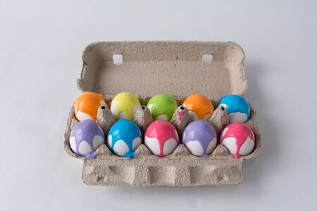 eggs painted with different colors are in an egg box on a white backgroundの写真素材