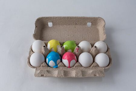 eggs painted with different colors are in an egg box on a white backgroundの写真素材