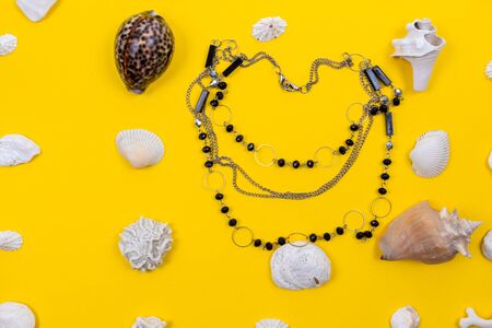 Beautiful necklaces are laid with shells. Costume jewelry is perfectly harmonises with yellow color. The composition looks modern and bright. These necklaces are suitable for any girl as a giftの写真素材