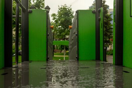 A childrens playground in a summer park in the rain. There are no adults or children. An empty Wet space. There is a lot of green vegetation around.High quality photoの写真素材