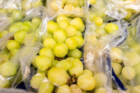 ripe white grapes lies bunches in opened plastic bags immediately for sale. Plenty of delicious juicy fruit. High quality photoの写真素材