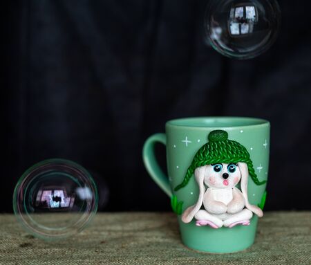 The original mug with decorative figurines made with their own hands. A lovely birthday present. Figures on the cup are fashioned hand made from colored clay. Soap bubbles around. High quality photoの写真素材