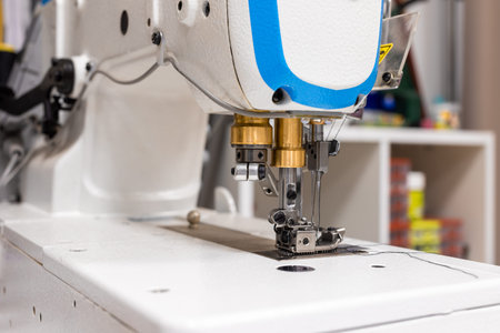 A professional sewing machine is in the workshop. Against the background of various devices and what...