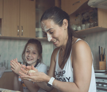 Mom and daughter have fun in the kitchen and cook together. Joyful and beautiful. High quality photo