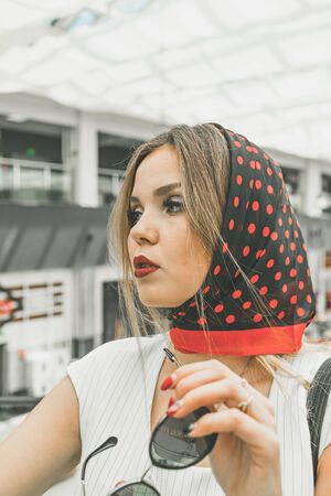 Portrait of a girl in a black headscarf in red polka dots. Beautiful European girl in a white suit in a normal urban setting. High quality photoの写真素材